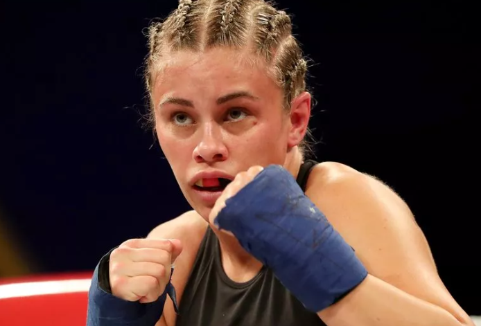 Paige VanZant in fighting stance with braided hair and blue hand wraps, ready to face the unpredictable 'elle brooke rough' style in their intense Misfits bout.
